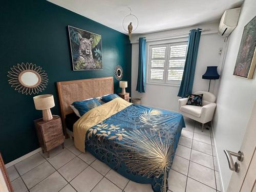 a bedroom with a bed and a chair in it at La Kaz à MaLou appartement de standing avec piscine et plage à 800m in Les Trois-Îlets