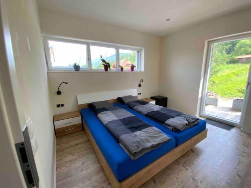 um quarto com uma cama azul num quarto com uma janela em Schöne Ferienwohnung in Windischgarsten em Windischgarsten