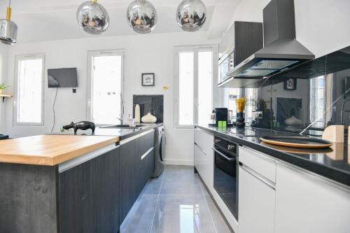 une cuisine avec des armoires noires et un comptoir dans l'établissement Appart 3 ch clim proche Vieux-Port Gare St-Charles, à Marseille