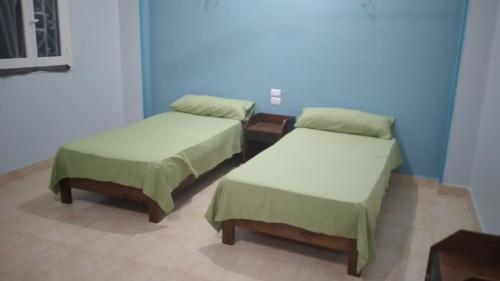 a room with two beds and a blue wall at Ali habou {4} in Luxor