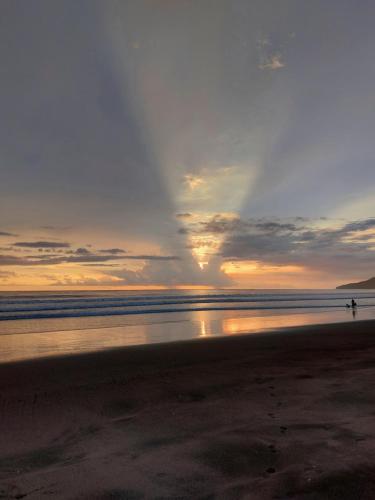 a person walking on the beach at sunset at Palm Beach Inn in Playa Grande