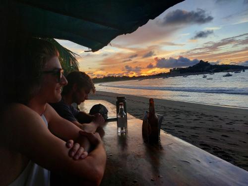 a group of people sitting at a table on the beach at Palm Beach Inn in Playa Grande