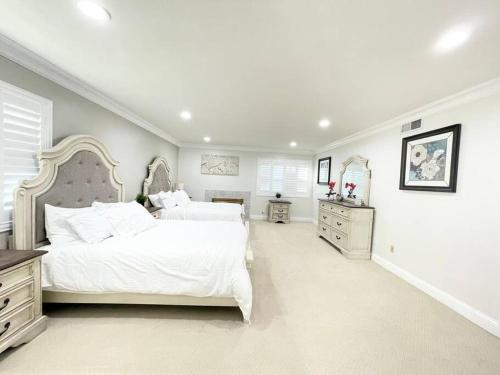 um grande quarto branco com 2 camas e 2 cómodas em Disneyland Fun Gathering Village for Large Family em Placentia