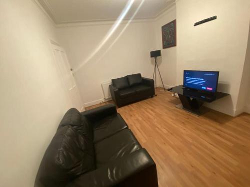 a living room with a leather couch and a television at London Recently Refurbished House in Thornton Heath