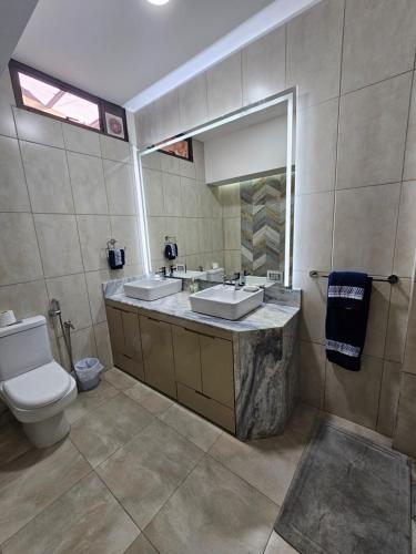a bathroom with two sinks and a toilet and a mirror at Lujoso PH con JACUZZY Privado in Guayaquil
