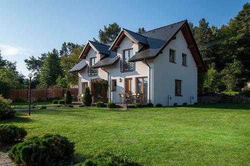 a white house with a black roof at 4 Pory Roku Apartamenty Domki Pokoje in Nadole