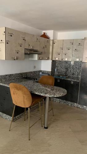 a kitchen with a counter with two chairs and a table at Appartement Meublée in Casablanca