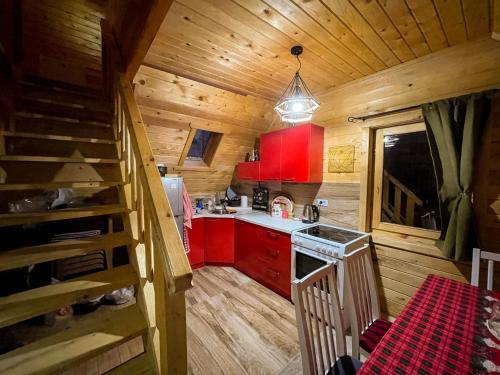 uma cozinha com armários vermelhos e uma escada numa cabina em Cozy Cabin in the Woods em Brezovicë