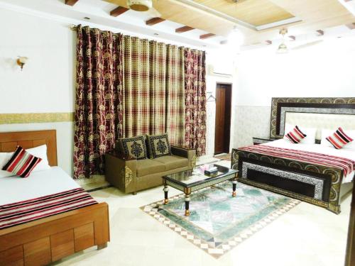 una sala de estar con 2 camas y un sofá. en Moon Palace Hotel Lahore, en Lahore