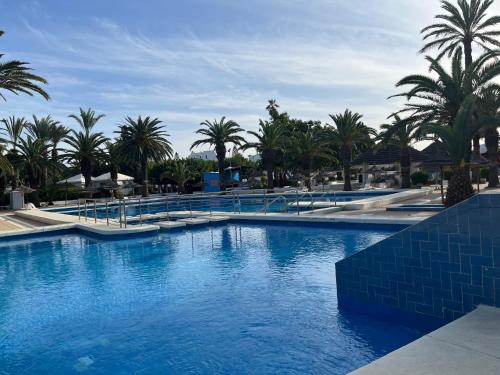 a large swimming pool with palm trees in a resort at Agréable villa proche de la mer a Chott Meriem in Chott Meriem