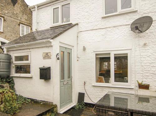 a white house with a door and a window at Daisy Cottage in Warminster