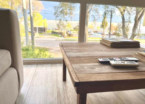 een houten tafel met twee afstandsbedieningen erop bij Espectacular departamento sobre la laguna para parejas in Chascomús