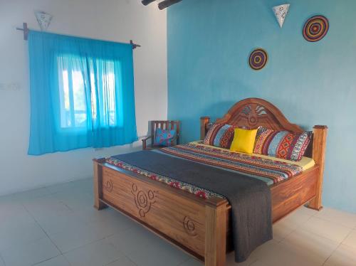 1 dormitorio con cama de madera y pared azul en SECRET PLACE HOTEL by HELLO TANZANIA TOURS& SAFARIS, en Makunduchi