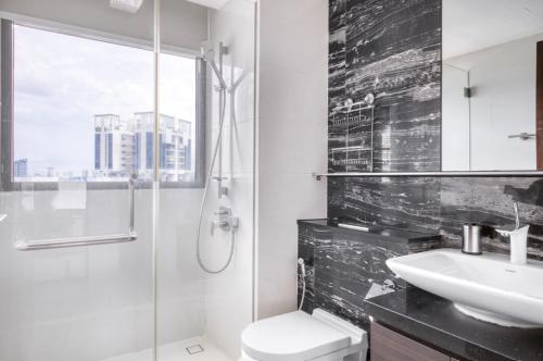 La salle de bains est pourvue d'un lavabo, de toilettes et d'une douche. dans l'établissement The Dapper Digs 2BR Apartment in Singapore, à Singapour