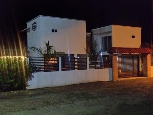 une maison blanche avec une clôture devant elle la nuit dans l'établissement Chiriguare parrilla, à Villavicencio