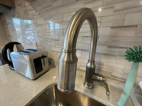 a kitchen sink with a faucet and a toaster at Modern studio with kitchenette and bath in Guelph