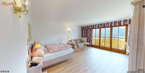 a bedroom with a bed and a desk and a window at Hotel Glocknerhof in Berg im Drautal