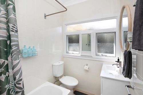 a white bathroom with a toilet and a sink at The Alfred, Mittagong in Mittagong