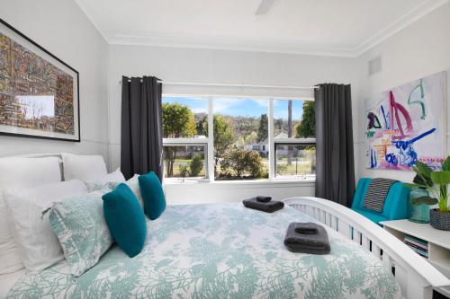 Un dormitorio con una cama con almohadas azules y una ventana en The Alfred, Mittagong, en Mittagong