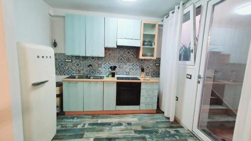 a kitchen with white cabinets and a stove top oven at NAUTILUS - monolocale seminterrato con finestre in Àrbatax