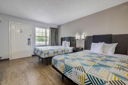 ein Hotelzimmer mit 2 Betten und einer Tür in der Unterkunft Studio 6-Arlington, TX - South - Dallas in Arlington