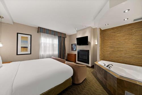 a hotel room with a large bed and a bathtub at Best Western Plus Orangeville Inn & Suites in Orangeville