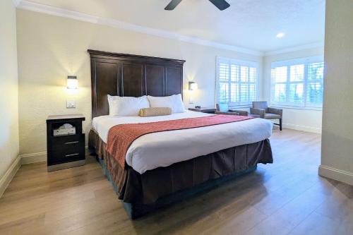 a bedroom with a large bed and a chair at Clarion Collection Wilkie's Inn Pacific Grove - Monterey in Pacific Grove
