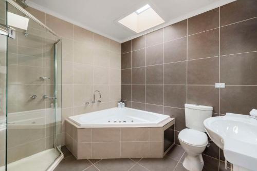 a bathroom with a tub and a toilet and a sink at Comfort Inn Clubarham in Barham