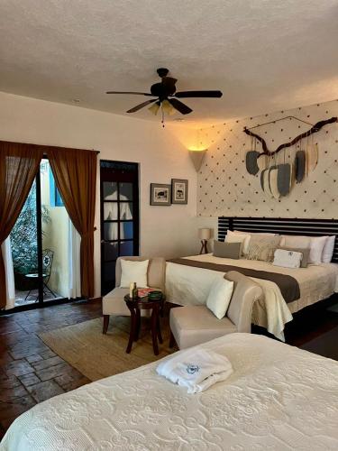 a bedroom with two beds and a couch and a ceiling fan at Casa Dos Lirios Hotel Boutique in Mérida