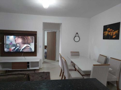 a living room with a television and a dining table at Apartamento belvedere do lago in Serra Negra