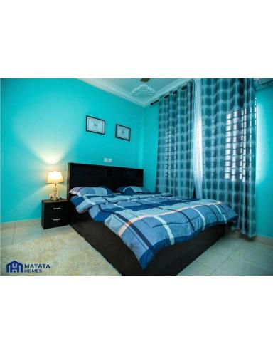 a blue bedroom with a bed and a lamp at Matata Homes Airbnb in Kasoa
