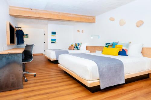 2 Betten in einem Zimmer mit einem Schreibtisch und einem TV in der Unterkunft Anacortes Inn in Anacortes