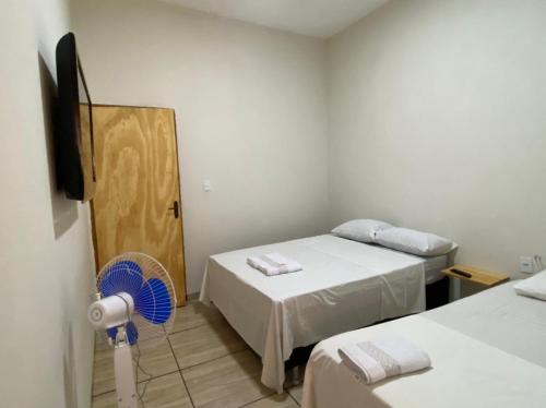 a room with two beds and a tv and a fan at Hotel Pousada Aeroporto in Ponta Porã
