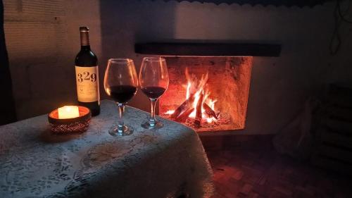 two glasses of wine sitting on a table next to a fireplace at Casa del monte, en cercanía de arroyo y balneario in Puerto Rico