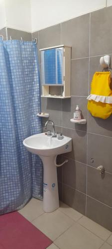 a bathroom with a sink and a blue shower curtain at Complejo Don Tito in San Juan