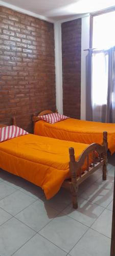 two beds with orange sheets in a room at Complejo Don Tito in San Juan