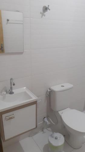 a white bathroom with a toilet and a sink at Cantinho da tati in Itu