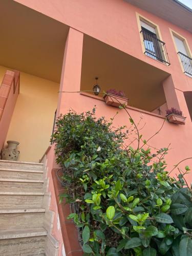 um edifício cor-de-rosa com escadas e plantas verdes em La Casa dell'Artista em Battifolle
