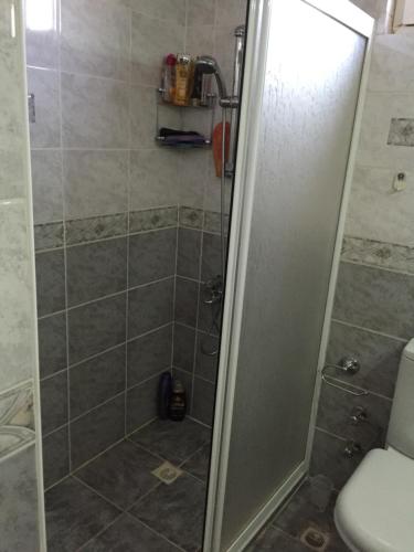 y baño con ducha y puerta de cristal. en Apartement met privé zwembad vlakbij vliegveld en Mandırlar