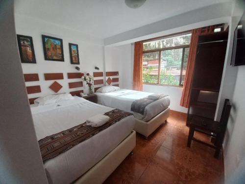 a bedroom with two beds and a window at PAQARIQ INN HOTEL in Machu Picchu