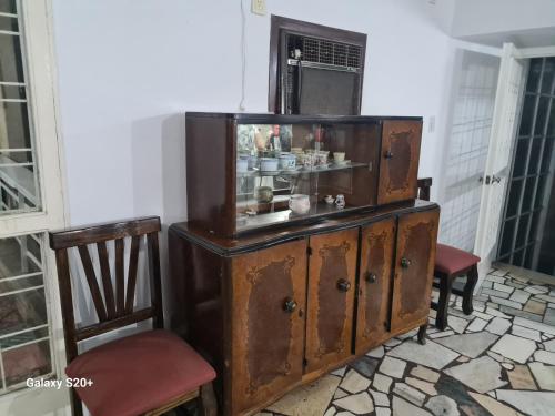 an old wooden cabinet in a room with two chairs at Casa Al pie del Cerro in Yerba Buena