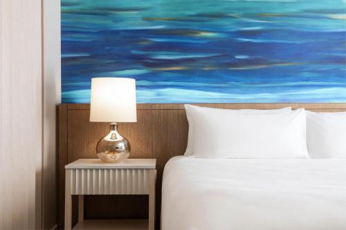a bedroom with a bed and a table with a lamp at Sheraton Waikiki Beach Resort in Honolulu