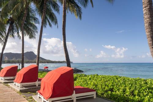 a row of chairs on the beach with palm trees at Sheraton Waikiki Beach Resort in Honolulu