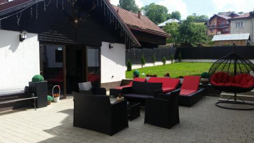 a patio with black and red chairs and a swing at Pensiunea Ellemar in Vatra Dornei