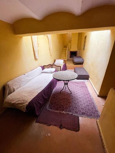 a group of beds in a room with a table at La Maison Haute Larache Morocco in Larache