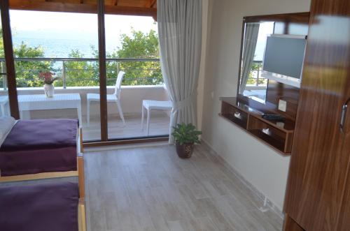 a living room with a television and a balcony at Ada Palas Otel in Marmara Adasi