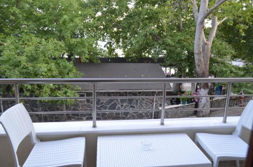 two chairs and a table on a balcony with trees at Ada Palas Otel in Marmara Adasi