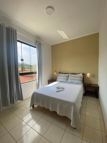 - une chambre avec un lit blanc et une grande fenêtre dans l'établissement Pousada da Mariinha, à São Lourenço