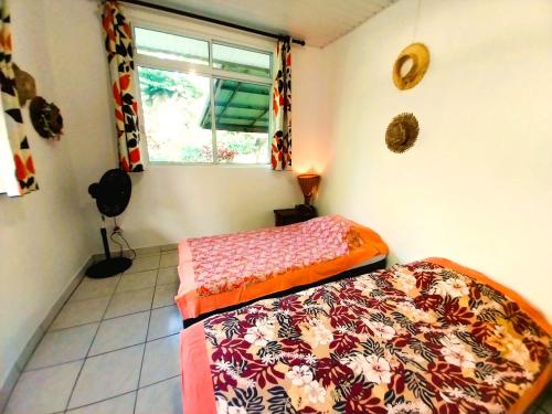 two beds sitting in a room with a window at TAHITI - Haumaru Beach Fare in Mahina