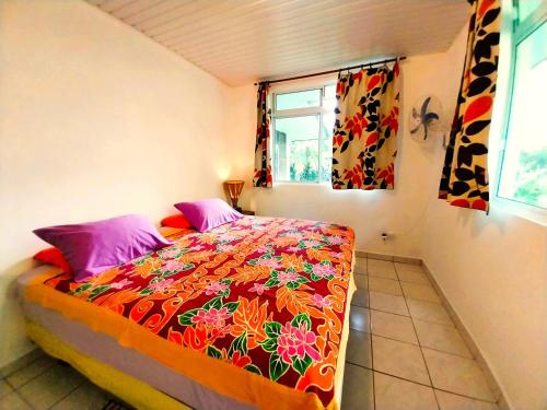 a bedroom with a bed with a colorful bedspread at TAHITI - Haumaru Beach Fare in Mahina